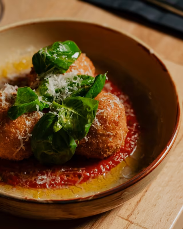 Arancini w glinianej misce z bazylią